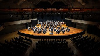 Konzertsaal mit Bühne im Mittelpunkt, auf der die Audi Bläserphilharmonie spielt